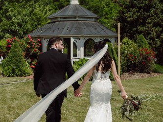 Bride and groom seen from behind walking to the Gazebo, her veil blowing in the wind, Jemira Richards photo